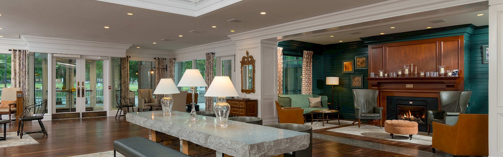 A spacious, stylish living area with natural light from a skylight, featuring a fireplace, seating, and elegant decor.