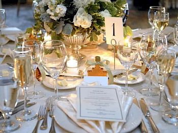 A beautifully set dining table with elegant glassware, a floral centerpiece, and a table number 