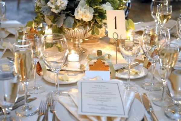 A beautifully set formal dining table with elegant glassware, silverware, a floral centerpiece, and a table number 