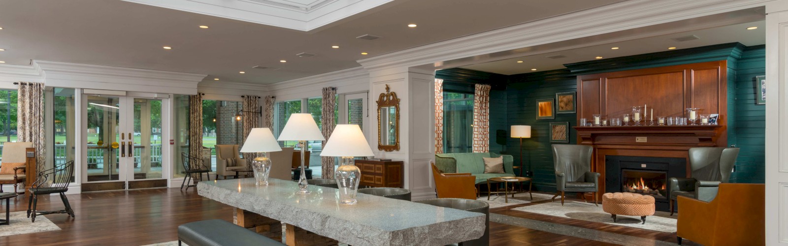 A spacious, well-lit living room with a skylight, fireplace, various seating areas, and elegant decor.