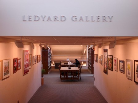 This image shows the Ledyard Gallery, with art displayed on both walls and a person sitting at a table in the center of the room.