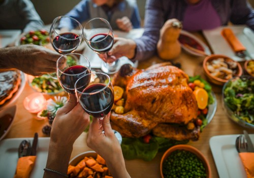 A festive meal with a roast turkey, various side dishes, and people toasting with red wine.