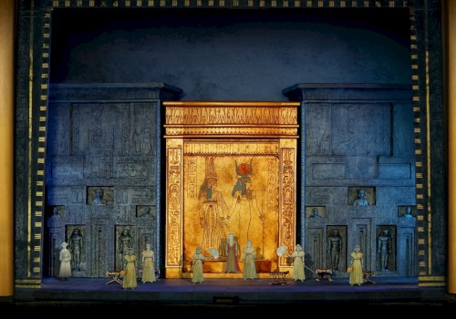 A stage set with an ancient Egyptian theme, featuring hieroglyphics, large golden doors, and performers in period costumes.