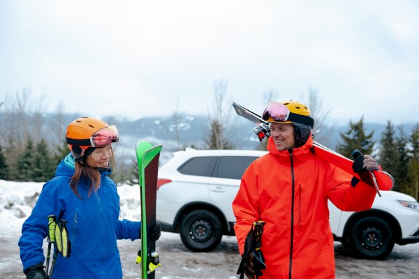 Snow outdoor picture of couple getting ready for skiing from their car