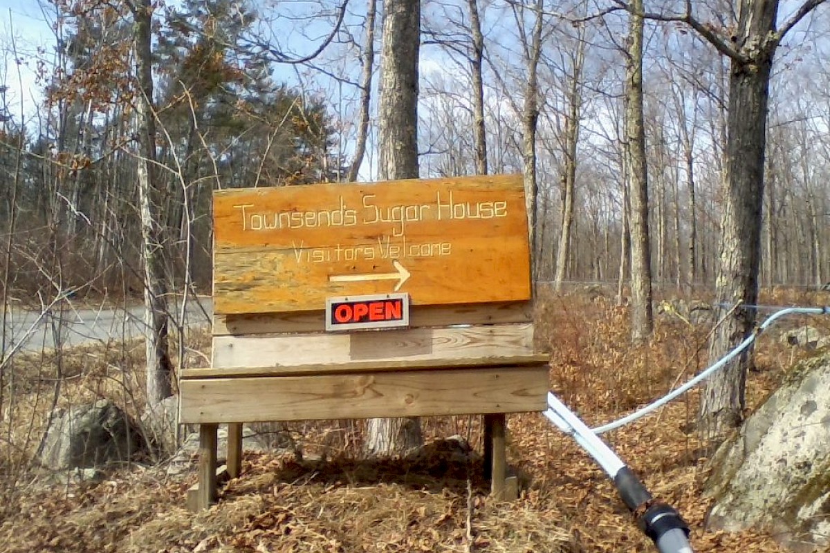 A wooden sign for Townsend's Sugar House with a maple leaf, arrow, 
