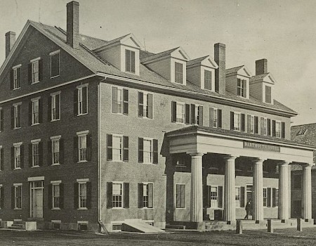 The image shows a historic three-story building with columns and dormer windows, labeled as Dartmouth College.