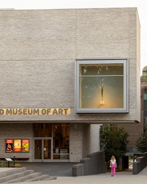The image shows the entrance of the Hood Museum of Art, featuring contemporary architecture and a display window.