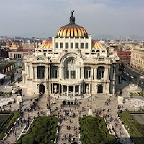 The image shows a grand building with a golden dome, marble architecture, and a busy public square in front, set in an urban environment.