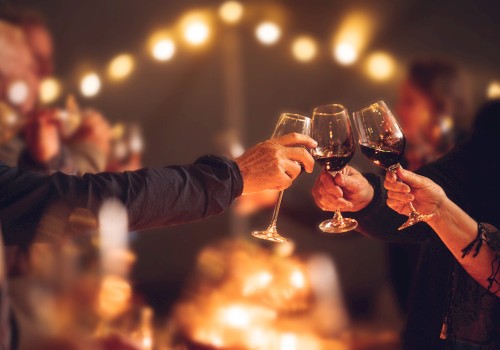 People are toasting with wine glasses in a warmly lit, festive setting, creating a cheerful and celebratory atmosphere.