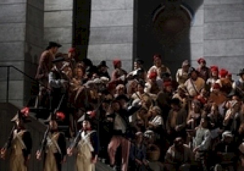 A staged scene with people in historical costumes on stairs, possibly from a theater or opera performance.
