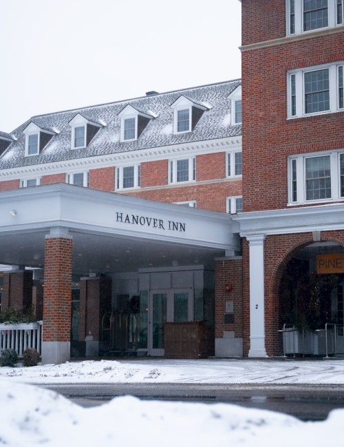 A snowy hotel entrance with a brick building, a covered driveway, and “Magnolia Inn” signage under a white canopy. End.