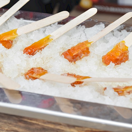 Colorful popsicles are cooling on ice in a tray.