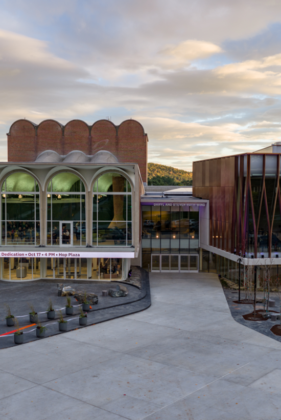 The image shows a modern building with large glass windows and unique architectural design, possibly part of a cultural or educational facility.