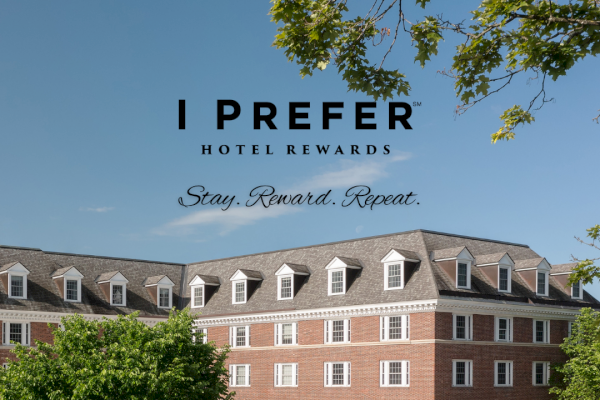 This is an image of the Hanover Inn, a hotel building with trees and a clear blue sky in the background.