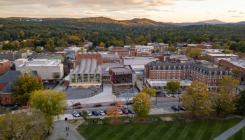 A small town with historic buildings, a park, and a mountain range in the background during sunset.